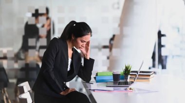 Ofiste otururken işten yorgun düşen iş kadınının yan görünüşü.