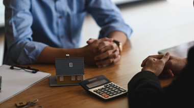 House broker 'ın modern ahşap masada otururken müşterisine poliçeyi açıklarken çekilmiş bir fotoğrafı. Kredi, Borç, Kredi, Alım veya Satım Anlaşması Konsepti.