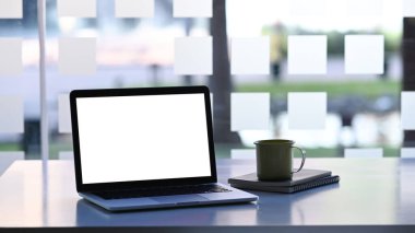Dizüstü bilgisayarı beyaz ekran ve beyaz masaya bir fincan kahve ile yapıştır..
