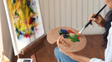 Sanat stüdyosunda oturmuş suluboya resim çizen bir kadın resmi..