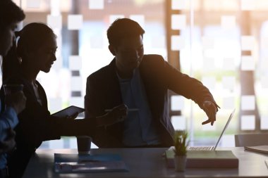 İşadamları dizüstü bilgisayar kullanıyor ve modern ofiste gelecek proje planı hakkında tartışıyorlar..