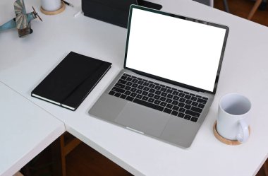 Boş ekran, defter ve kahve fincanını beyaz ofis masasına dizin..