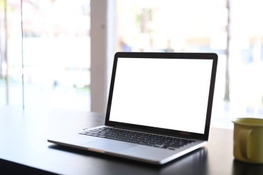 Boş ekran ve siyah tahta masa üzerinde kahve fincanı olan dizüstü bilgisayarı olan basit bir çalışma alanı..