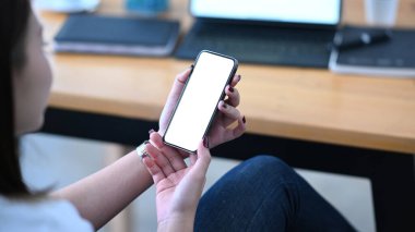 Genç bir kadın rahat işyerinde oturuyor ve cep telefonu kullanıyor. Reklam metni için beyaz boş ekran.