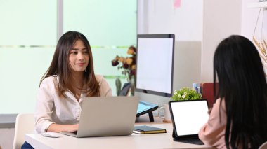 Yaratıcı ofiste çalışan ve yan yana oturan iki genç tasarımcı.