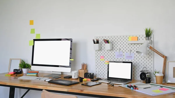 stock image Photo of Graphic designer working table and graphic designing equipment putting on it. White blank screen laptop and Computer display leave space for ads concept. Messy working desk concept.