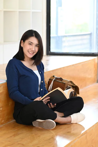 도서관에 앉아서 카메라 앞에서 아시아 여대생의 — 스톡 사진