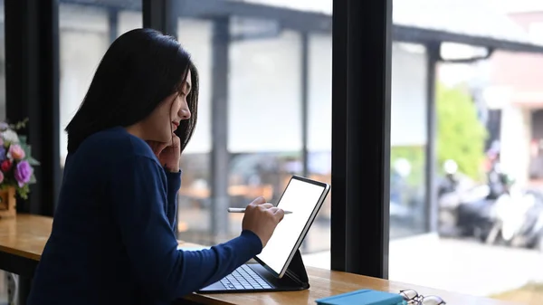 サイドビュー窓側に座っている間タブレットコンピュータで作業若い女性デザイナー — ストック写真