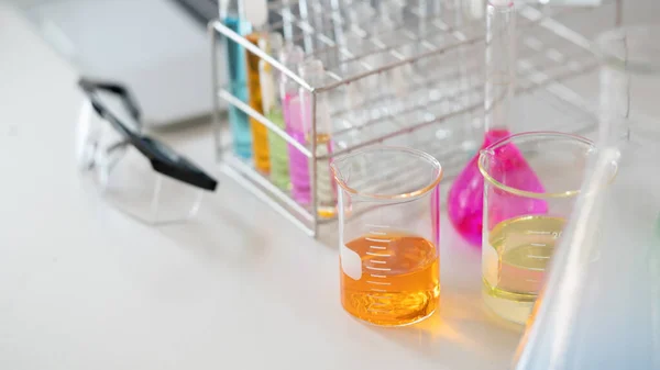 Zdjęcie Laboratoryjnych Wyrobów Szklanych Zawierających Kolorowe Płyny Okulary Ochronne Podczas — Zdjęcie stockowe