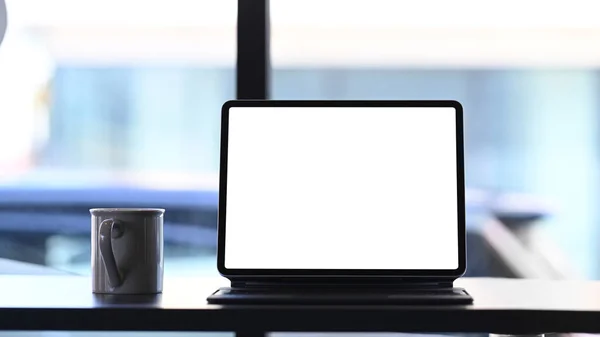 木製テーブルの上に空白の画面とコーヒーカップとモックアップタブレットコンピュータのフロントビュー — ストック写真