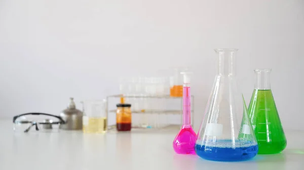 实验室玻璃器皿的照片 装有彩色液体和安全玻璃 放在白色桌子上 独立的白色背景 科学实验工具概念 — 图库照片
