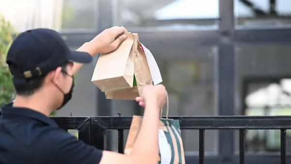 보호용 마스크를 문간에서 고객에게 음식을 배달하는 아시아의 배달부 — 스톡 사진