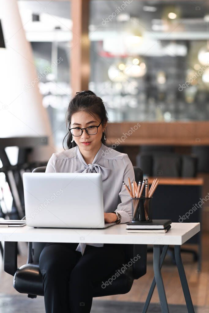 Portrait of businesswoman working on laptop computer at modern workplace.