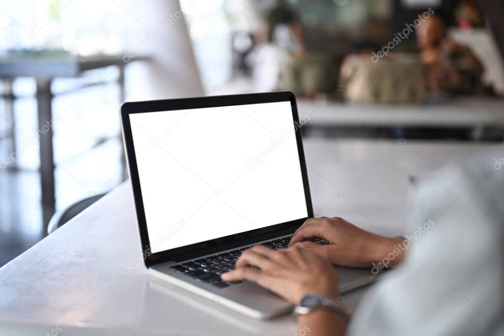 Close up view young woman hands typing on keyboard of laptop computer. White empty screen for advertise text.