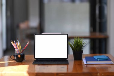 Tableti kablosuz klavye, kırtasiye malzemesi ve not defteriyle ahşap ofis masasına yapıştır.