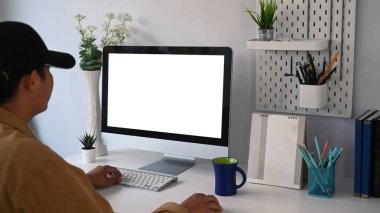 Genç adam modern işyerinde oturuyor ve bilgisayarla online çalışıyor..