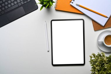 Beyaz arka planda dijital tablet ve ofis malzemeleriyle modern beyaz ofis masası.
