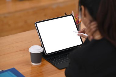 Stylus kalem tutan iş kadını tahta ofis masasında bilgisayar tabletiyle çalışıyor..