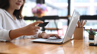 İş kadını bilgisayar kullanıyor ve elinde kredi kartı tutuyor çevrimiçi ödeme yapıyor ya da internetten alışveriş yapıyor..