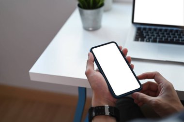 Bilgisayarla çalışan ve cep telefonu kullanan genç bir adamın yakın görüntüsü. Reklam metniniz için boş ekran.