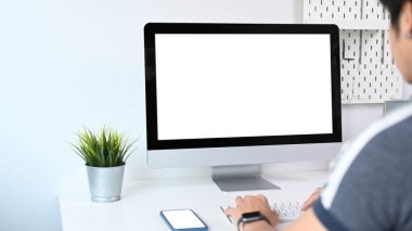 Genç adamın iş yerinde rahat bir şekilde oturması ve modern bilgisayar üzerinde çalışması..