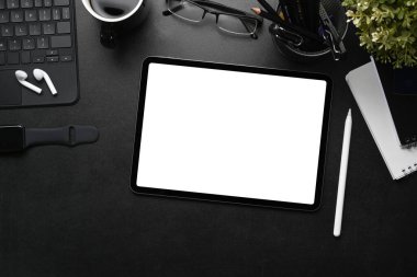 Dijital tablet, stilus kalem, kulaklık ve siyah deri üzerinde akıllı saat ile modern karanlık işyeri görünümünün üzerinde.
