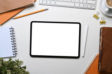 Yatay olarak, beyaz ofis masasında ofis malzemelerini çevreleyen boş ekran tableti ile dijital tablet oluşturun.