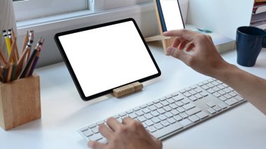 İnternette dijital tabletle çalışan genç adam merkez ofisteki beyaz masada..