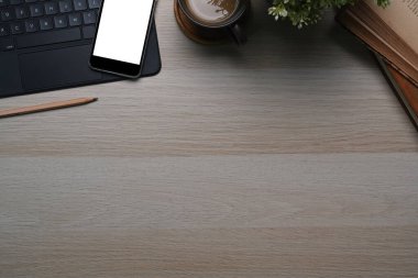 Rahat iş yeri, akıllı telefon, kablosuz klavye, not defteri, kahve fincanı reklam alanı ahşap masa üzerinde..