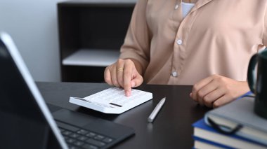 Dijital tabletle çalışan ve ofis masasında iş verilerini hesaplayan kırpılmış bir muhasebeci..