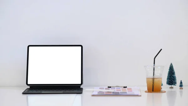 Graphic designer workplace with tablet computer, paperwork and coffee cup on white table.