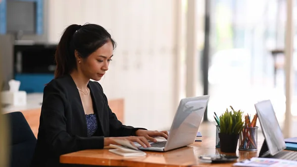 オフィスの机に座っている間 ラップトップコンピュータで彼女のプロジェクトに取り組んでいる若いアジアの実業家 — ストック写真