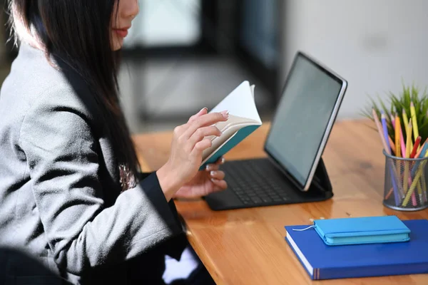 コンピュータテーブルとノートブックで情報を探して働く若い女性のオフィスワーカーの作物のショット — ストック写真