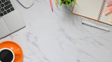 Seramik kahve fincanının üst görüntüsü, saksı bitkisi, not, kalem ve kalemlerin mermer dokuma masasında bir araya getirilmesi. Yaratıcı işyeri kavramı.