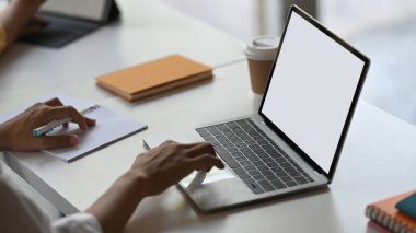 Sekreter kadının ellerinin bilgisayar laptopuna beyaz ekranla yazı yazıp notlar, kahve fincanı ve bir yığın kitapla çevrili düzenli çalışma masasına yerleştirdiği görüntüler..