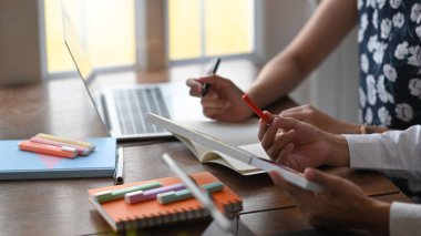 Renkleri seçerken ve düzenli oturma odası üzerinde ahşap çalışma masasında otururken projeleri hakkında konuşan / tartışan / beyin fırtınası yapan grafik tasarımcı ekibinin kırpılmış görüntüsü.