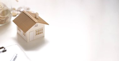 Ev modelinin fotoğrafı, pano, vazodan tasarruf edilen para beyaz masaya konuyor. Ev konsepti almayı planlıyorum..