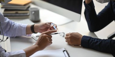 Doktorun modern klinikteki çalışma masasında otururken hastasına virüs ve salgın hakkında konuşan / açıklayan genç doktorun görüntüsü..