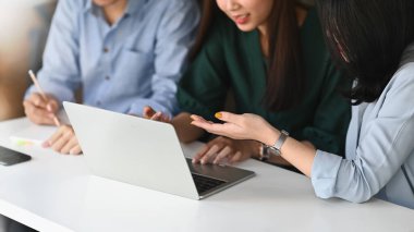 Ux Ui geliştirme ekibinin fotoğrafı, arka plan olarak rahat ve düzenli dekorasyon ofisiyle birlikte modern çalışma masasında tartışırken / buluşurken / çalışırken vurguladı.