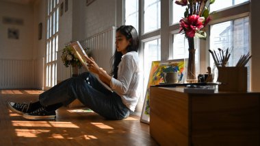 Arkaplan olarak klasik sanat stüdyosunun üzerine resim çizerken yerde sanatçı olarak çalışan güzel bir kadının fotoğrafı..