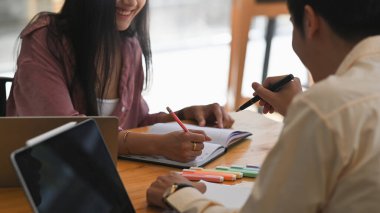 Modern ofis üzerinde ahşap çalışma masasında yan yana otururken yeni meslektaşını eğitirken / eğitirken / öğretirken çekilmiş bir fotoğraf..