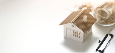 Ev modelinin fotoğrafı, pano, vazodan tasarruf edilen para beyaz masaya konuyor. Ev konsepti almayı planlıyorum..