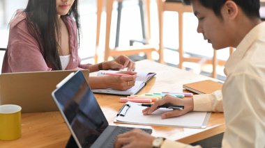 Modern ofis üzerinde ahşap çalışma masasında yan yana otururken yeni meslektaşını eğitirken / eğitirken / öğretirken çekilmiş bir fotoğraf..