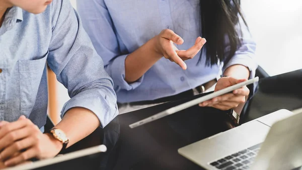 Cropped image of business developer team working together by using a computer tablet and laptop while sitting at the modern working desk over comfortable office as background.