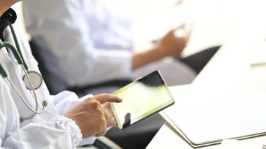 Bilgisayar dizüstü bilgisayarı ve tabletle çalışan araştırmacı ekibinin kırpılmış görüntüsü modern laboratuvar üzerinde çalışırken arka plan olarak beyaz çalışma masasında.