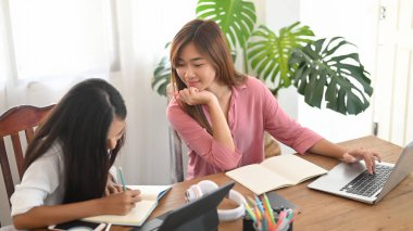 Kadınlar tahta masada yan yana otururken bilgisayar tableti ve dizüstü bilgisayar kullanıyorlar..