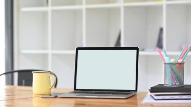 Beyaz ekran bilgisayar dizüstü bilgisayar ve ofis ekipmanlarıyla çevrili rahat bir çalışma alanı.