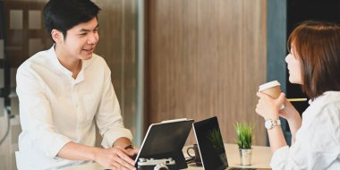 Bilgisayar ve bilgisayar tabletleriyle çalışan genç bir çiftin modern ve rahat oturma odasında arka plan olarak yan yana otururken çekilmiş fotoğrafı..