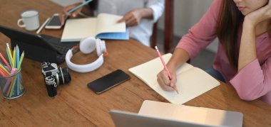 Kırpılmış kadın görüntüsü ahşap çalışma masasında çalışan bir bilgisayarla birlikte çalışıyor..