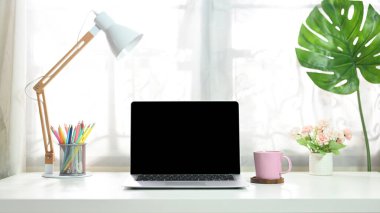 Boş bir bilgisayar, oturma odasındaki beyaz çalışma masasına yerleştiriliyor..